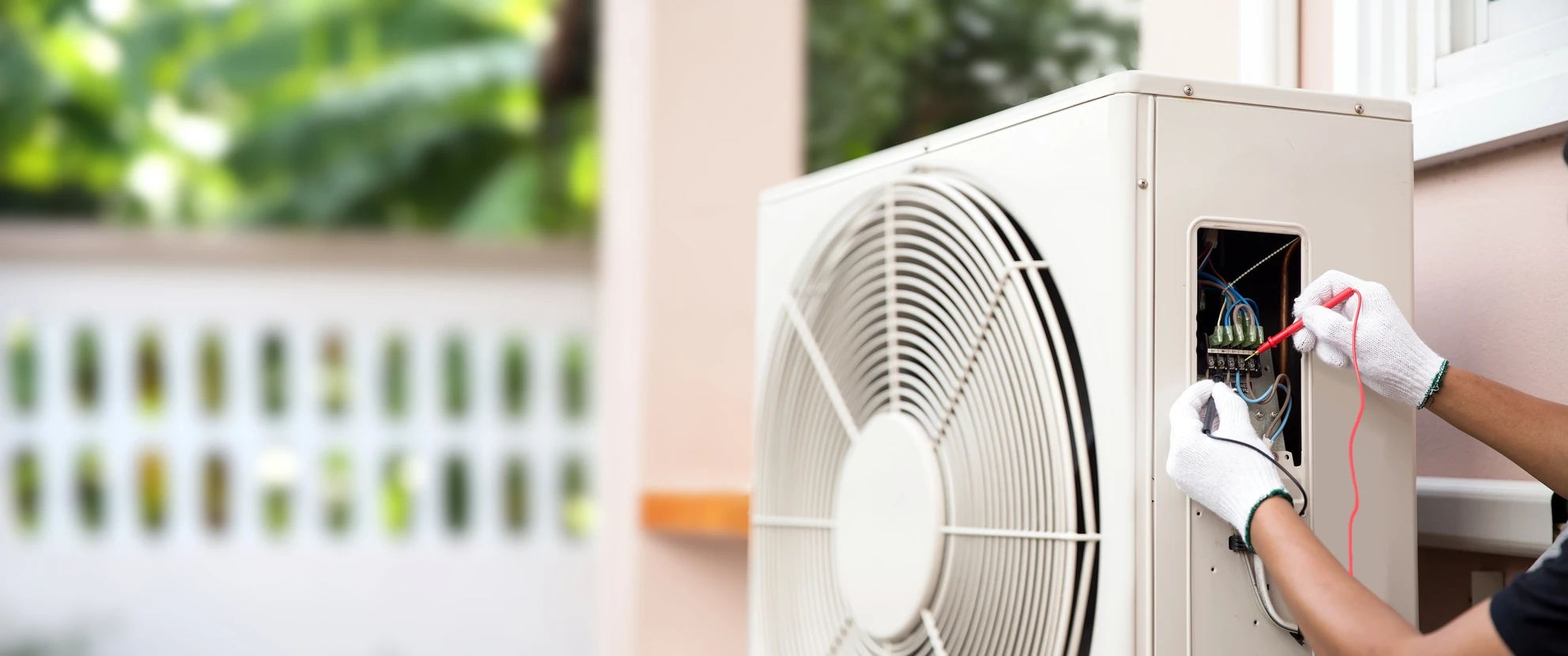 Extérieur résidentiel avec technicien effectuant maintenance sur unité de climatisation