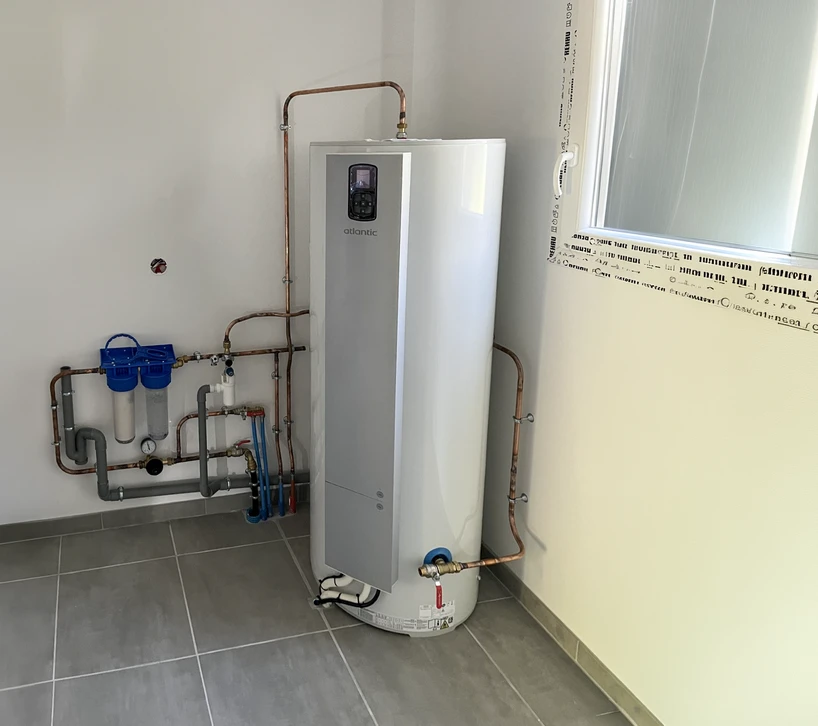 Scène extérieure montrant un chauffe-eau solaire installé sur une toiture en tuiles méditerranéennes