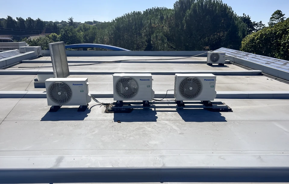 Technicien en combinaison bleue effectuant la maintenance d'un climatiseur mural dans un int&eacute;rieur r&eacute;sidentiel moderne