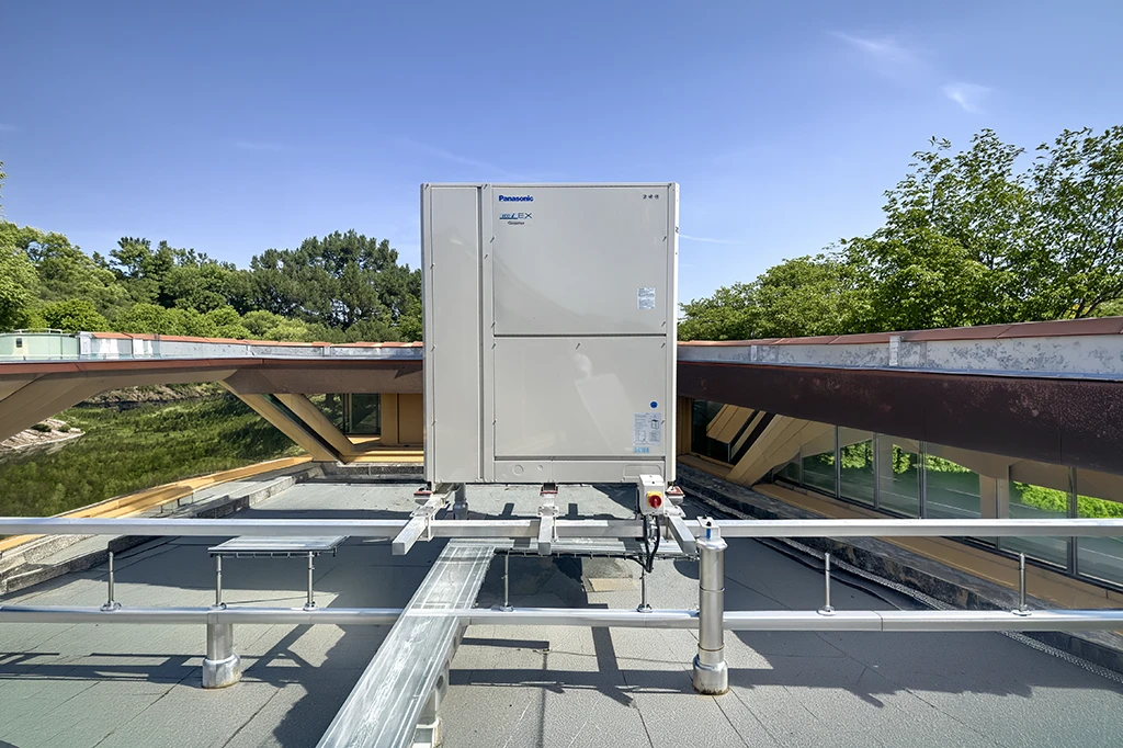 Chantier de couverture en cours, vue extérieure d'une toiture en pente avec ouvrier installant des tuiles terre cuite