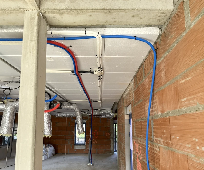 Chantier de couverture en cours, vue extérieure d'une toiture en pente avec ouvrier installant des tuiles terre cuite