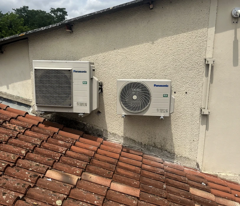 Chantier de couverture en cours, vue extérieure d'une toiture en pente avec ouvrier installant des tuiles terre cuite