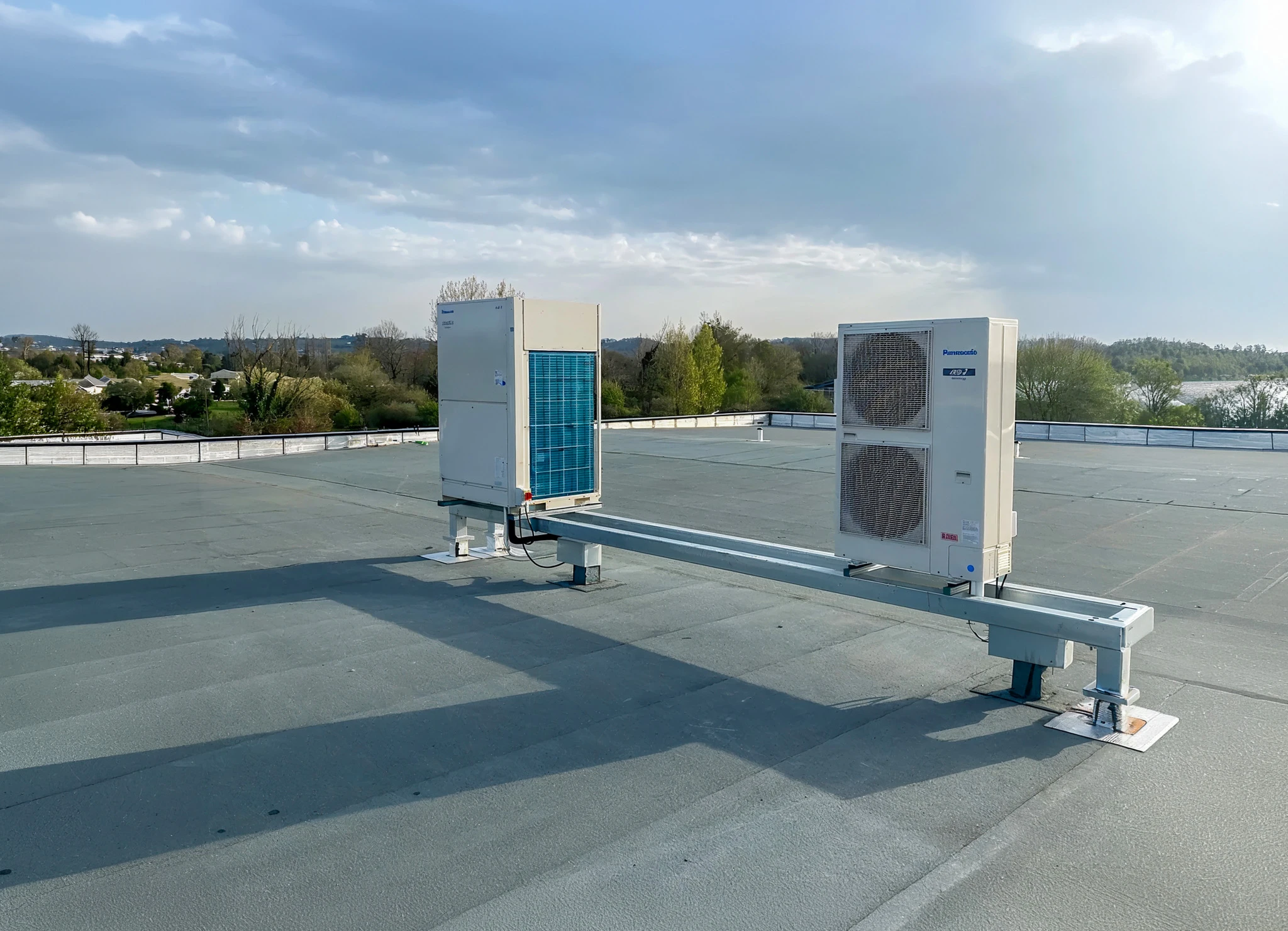 Ext&eacute;rieur d'un b&acirc;timent avec unit&eacute; de climatisation commerciale blanche &agrave; double ventilateur install&eacute;e sur dalle b&eacute;ton